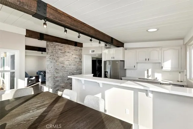 a large kitchen with stainless steel appliances kitchen island granite countertop a refrigerator a stove a sink and white cabinets with wooden floor