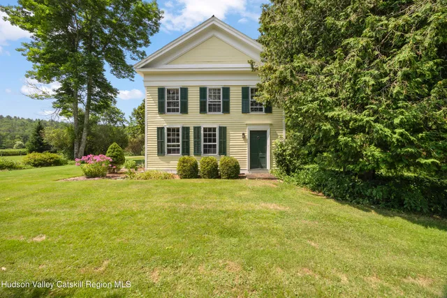 a front view of a house with a yard and trees