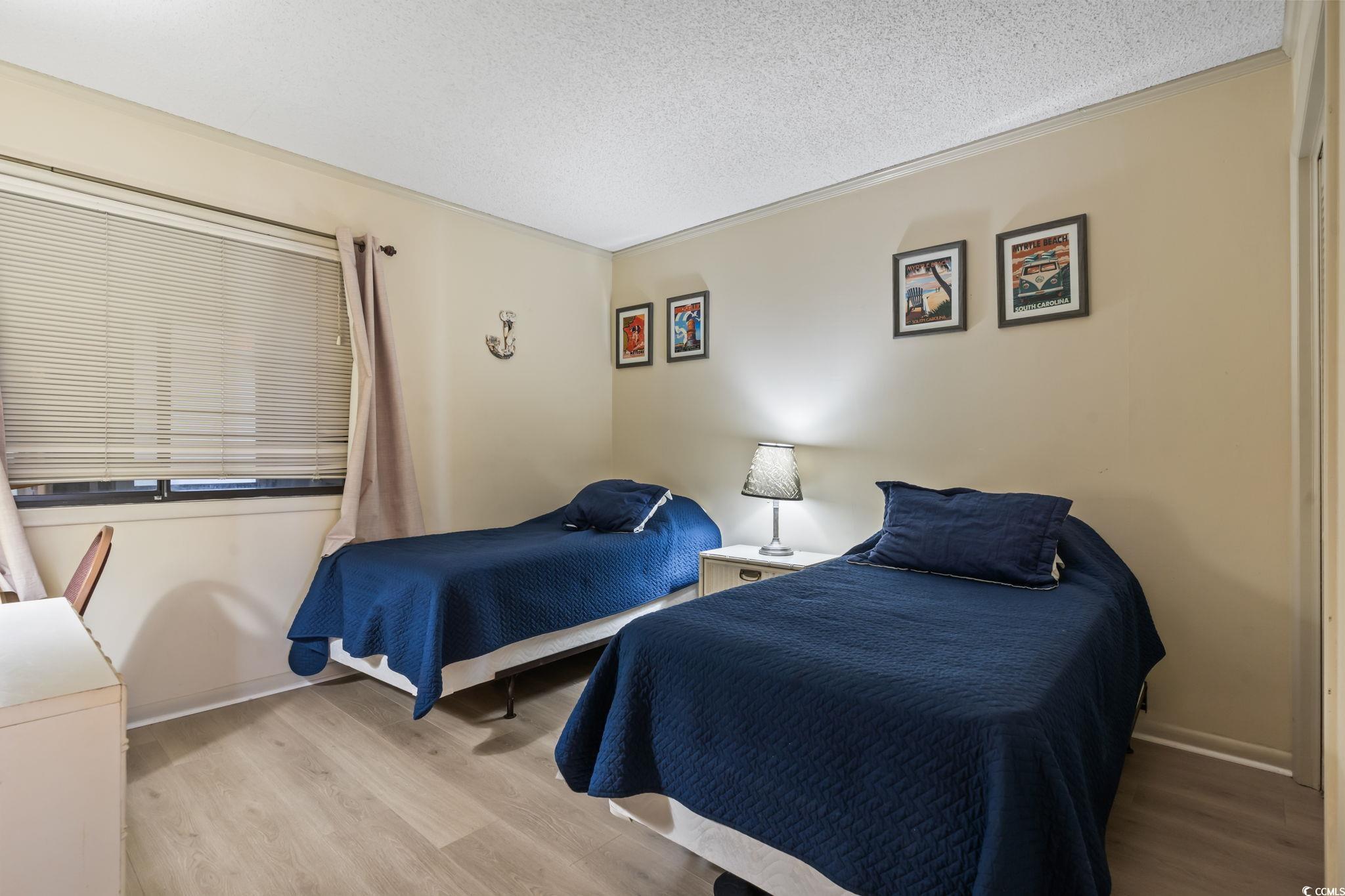 1780 North Waccamaw Drive, Unit 109 Murrells Inlet, SC 29576 - Photo 6 of 19 Bedroom with a textured ceiling, light wood-style floors, and ornamental molding
