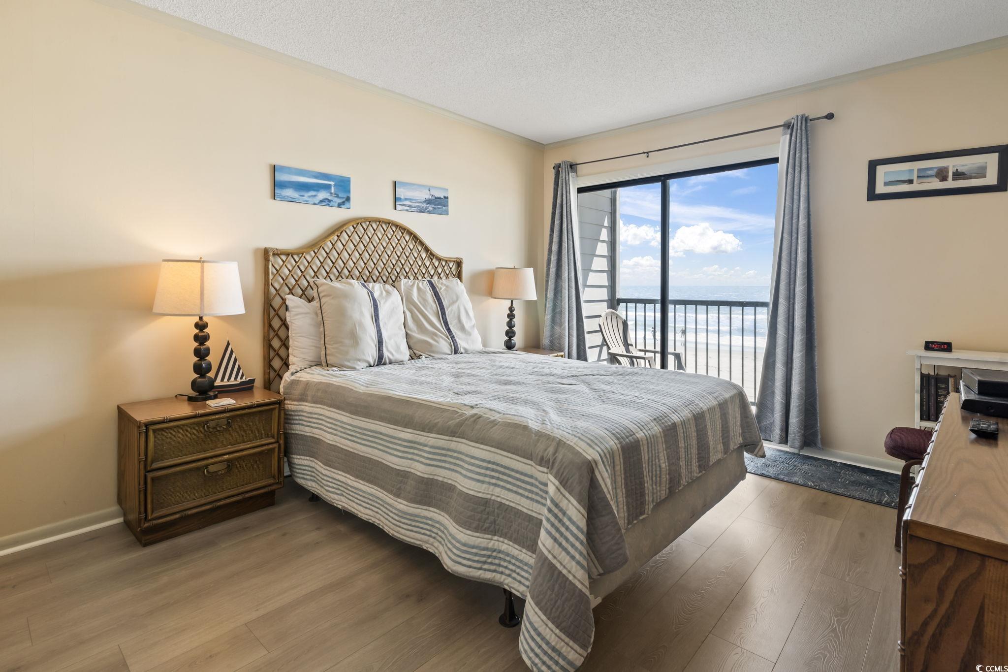 1780 North Waccamaw Drive, Unit 109 Murrells Inlet, SC 29576 - Photo 9 of 19 Bedroom with a water view, a textured ceiling, wood finished floors, and access to outside