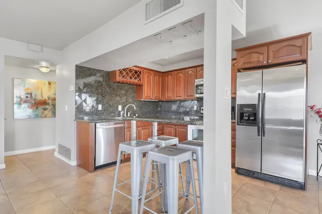 a kitchen with stainless steel appliances granite countertop a refrigerator and a stove top oven