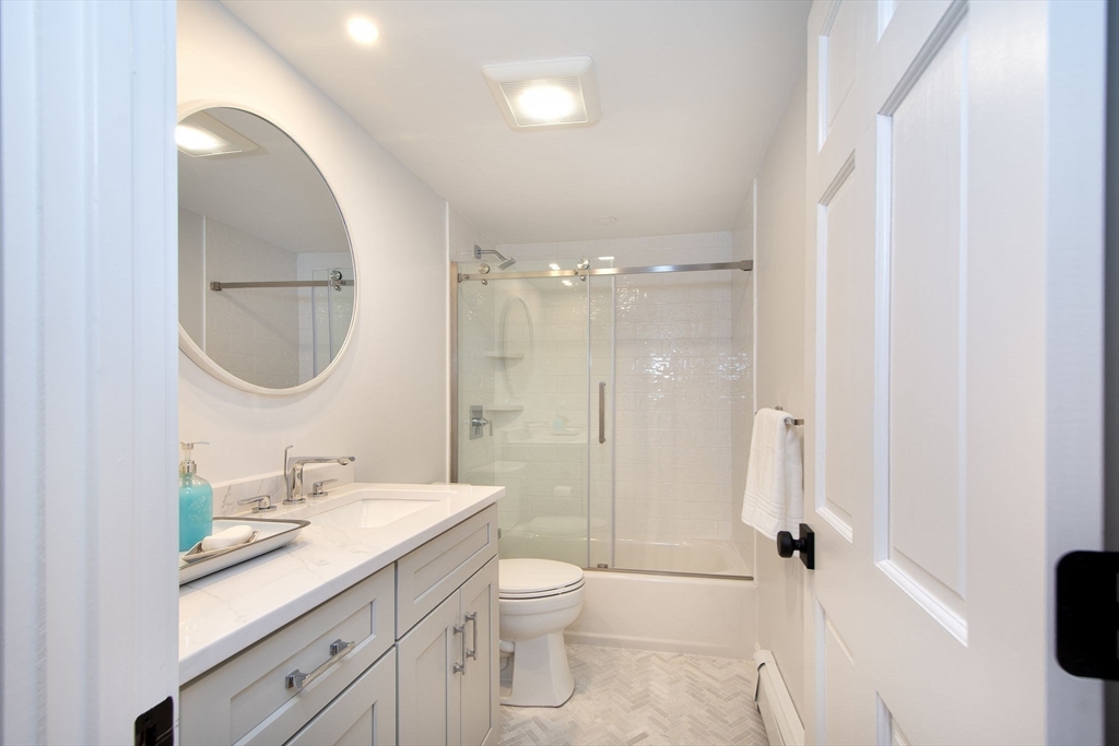 64 Cross Street Hingham, MA 02043 - Photo 12 of 23 a bathroom with a toilet a sink a mirror a shower a vanity and window