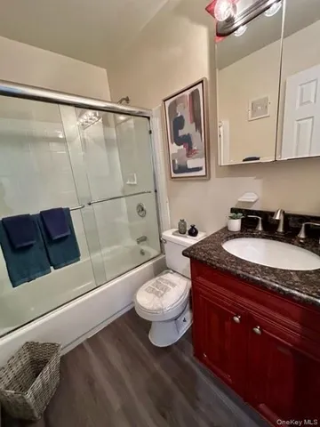 a bathroom with a granite countertop sink a toilet a mirror and shower