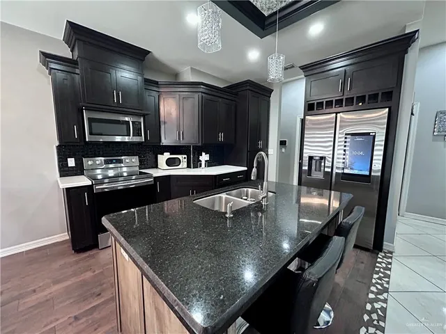 a kitchen with a stove a sink dishwasher a refrigerator and a dining table with wooden floor