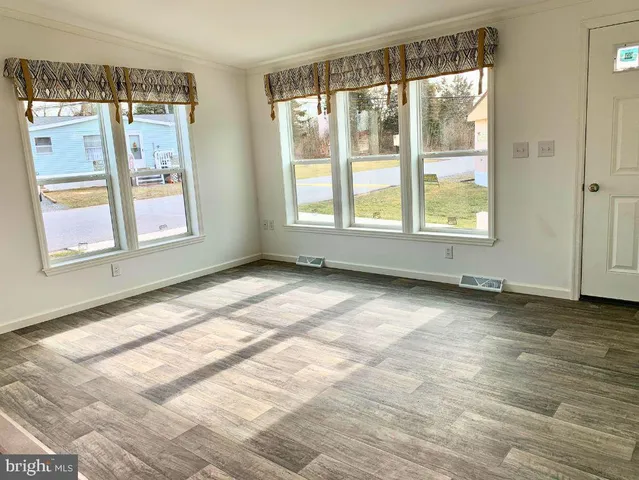 a view of an empty room with a window and wooden floor