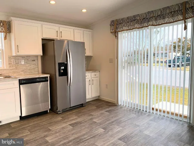 a kitchen with granite countertop a refrigerator a sink and white cabinets