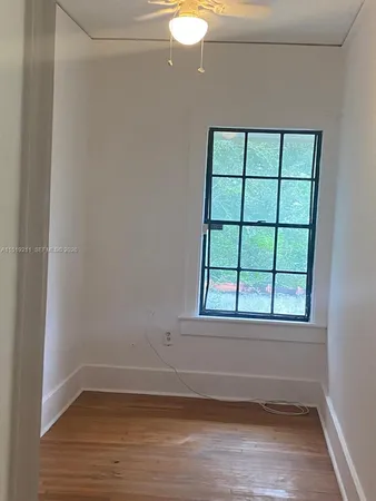a view of empty room with wooden floor and fan