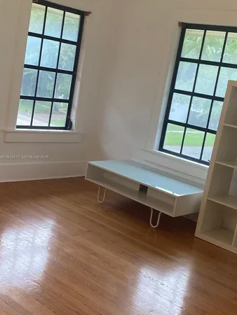 an empty room with windows and wooden floor