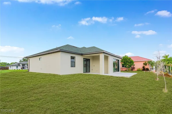 a white house with a big yard and large trees