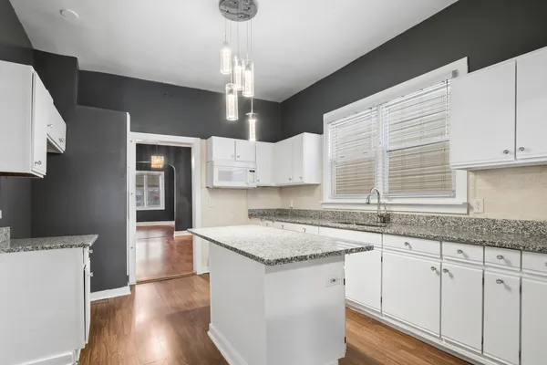 a kitchen with granite countertop white cabinets white appliances a sink and dishwasher