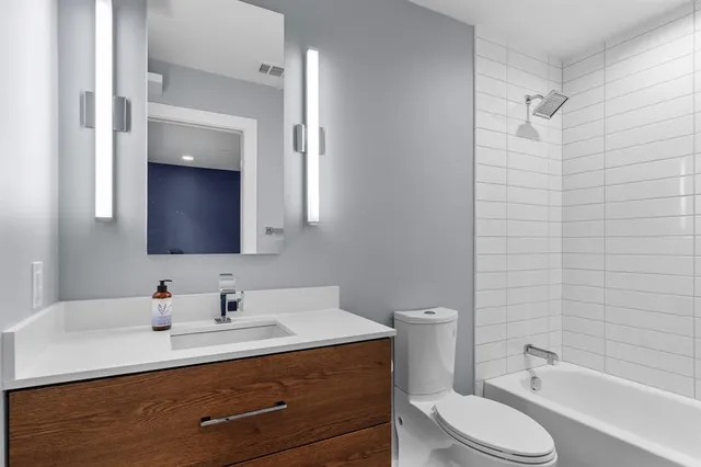 a bathroom with a granite countertop sink toilet a large mirror a shower and a bathtub