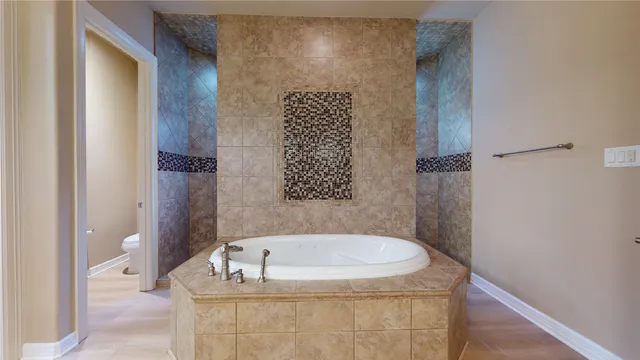 a bathroom with a bathtub shower sink vanity mirror and toilet