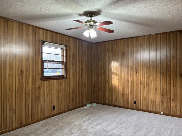 a view of an empty room with a ceiling fan and window