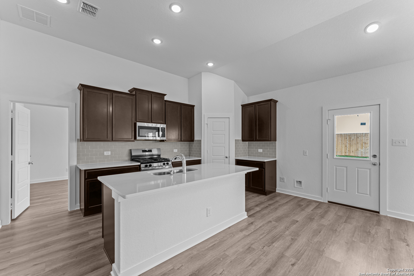 3022 Selhurst Street Converse, TX 78109 - Photo 6 of 32 a kitchen with stainless steel appliances a stove top oven a sink a refrigerator white cabinets and wooden floor