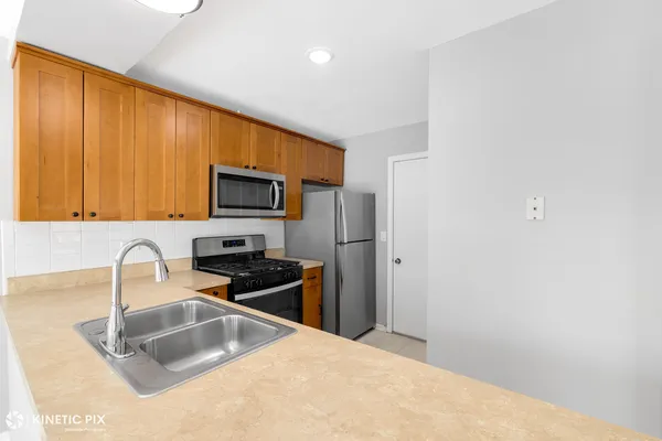 a kitchen with granite countertop a sink cabinets and stainless steel appliances