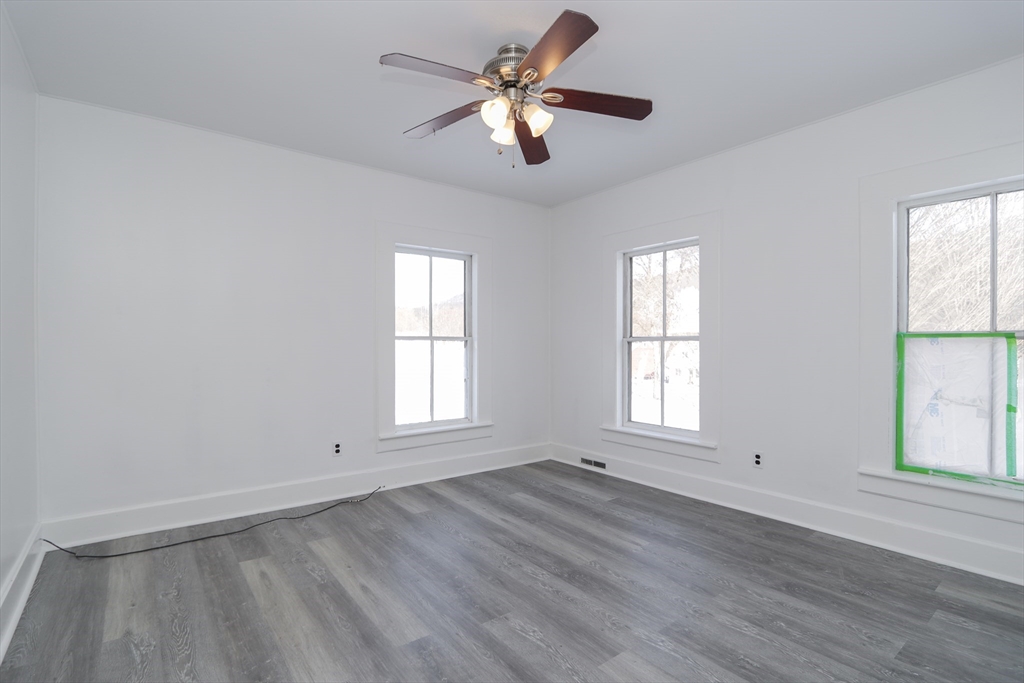 56 Middlefield Road Chester, MA 01011 - Photo 15 of 38 an empty room with wooden floor chandelier fan and windows