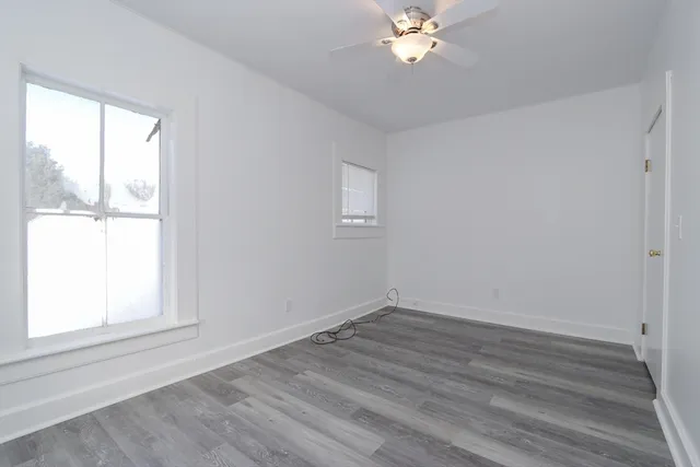 a view of an empty room with wooden floor and a window