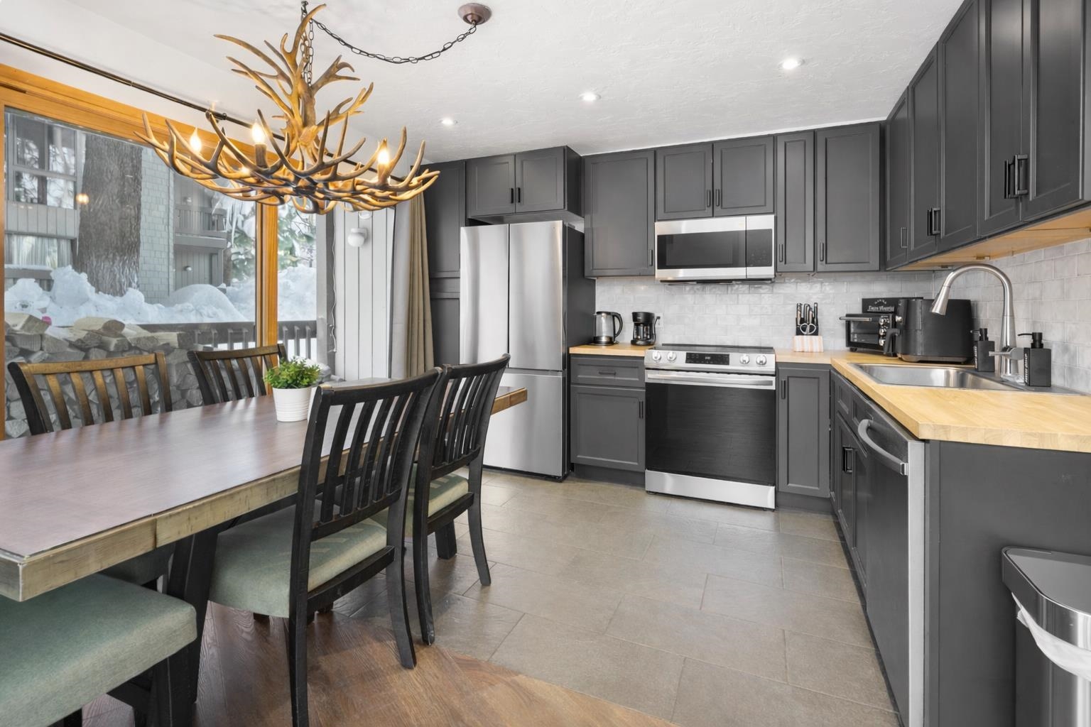286 Old Mammoth Road, Unit 19 Mammoth Lakes, CA 93546 - Photo 3 of 19 a kitchen with stainless steel appliances granite countertop a sink a stove a refrigerator cabinets a dining table and chairs