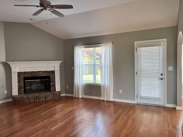 a view of a livingroom with a fireplace wooden floor and a window