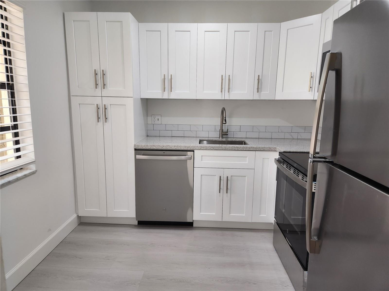 138 South Cypress Road, Unit 217 Pompano Beach, FL 33060 - Photo 13 of 21 a kitchen with white cabinets and stainless steel appliances