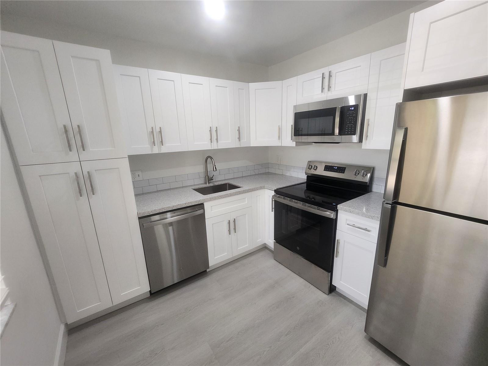 138 South Cypress Road, Unit 217 Pompano Beach, FL 33060 - Photo 2 of 21 a kitchen with white cabinets and white appliances