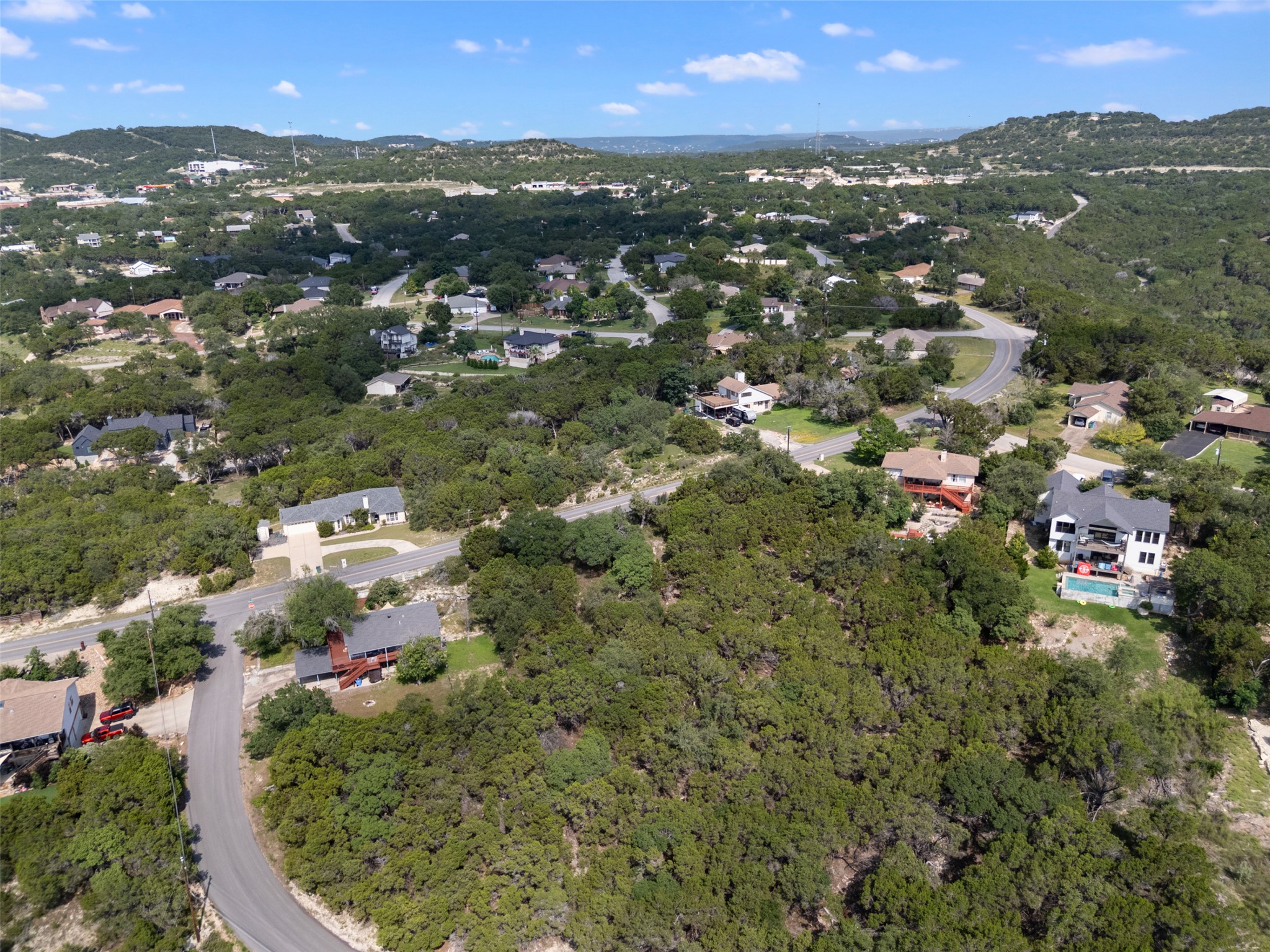 21105 Ridgeview Road Lago Vista, TX 78645 - Photo 11 of 34 Perched on a verdant hillside, this property offers panoramic views of a sprawling, tree-filled neighborhood with winding roads and distant hills.
