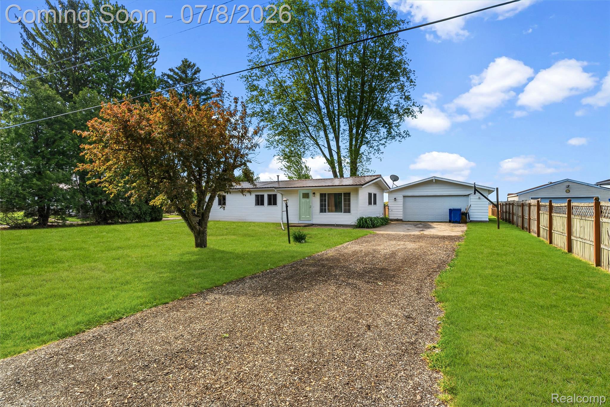 5698 McGrandy Road Bridgeport, MI 48722 - Photo 3 of 26 White exterior with multiple windows, featuring a gravel driveway, attached garage, and a large front lawn with mature trees