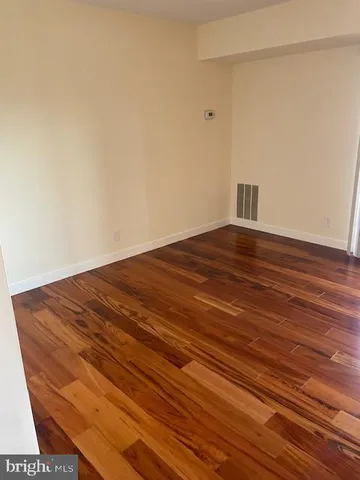 a view of empty room with wooden floor and floor to ceiling window