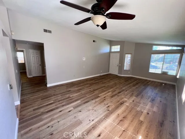 a view of an empty room with window and wooden floor