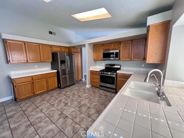 a kitchen with stainless steel appliances a sink a stove top oven a refrigerator and cabinets