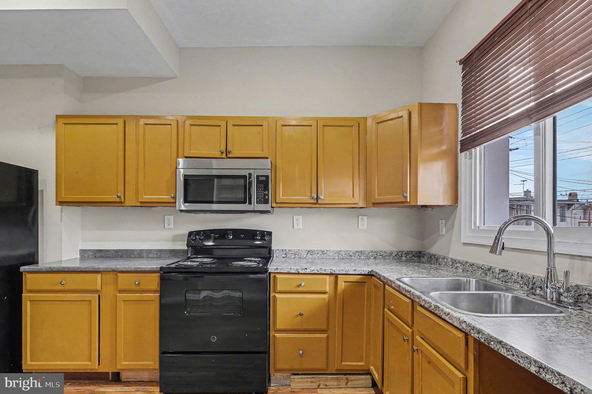 3418 East Baltimore Street Baltimore, MD 21224 - Photo 14 of 40 a kitchen with granite countertop a sink stainless steel appliances wooden cabinets and a counter top space