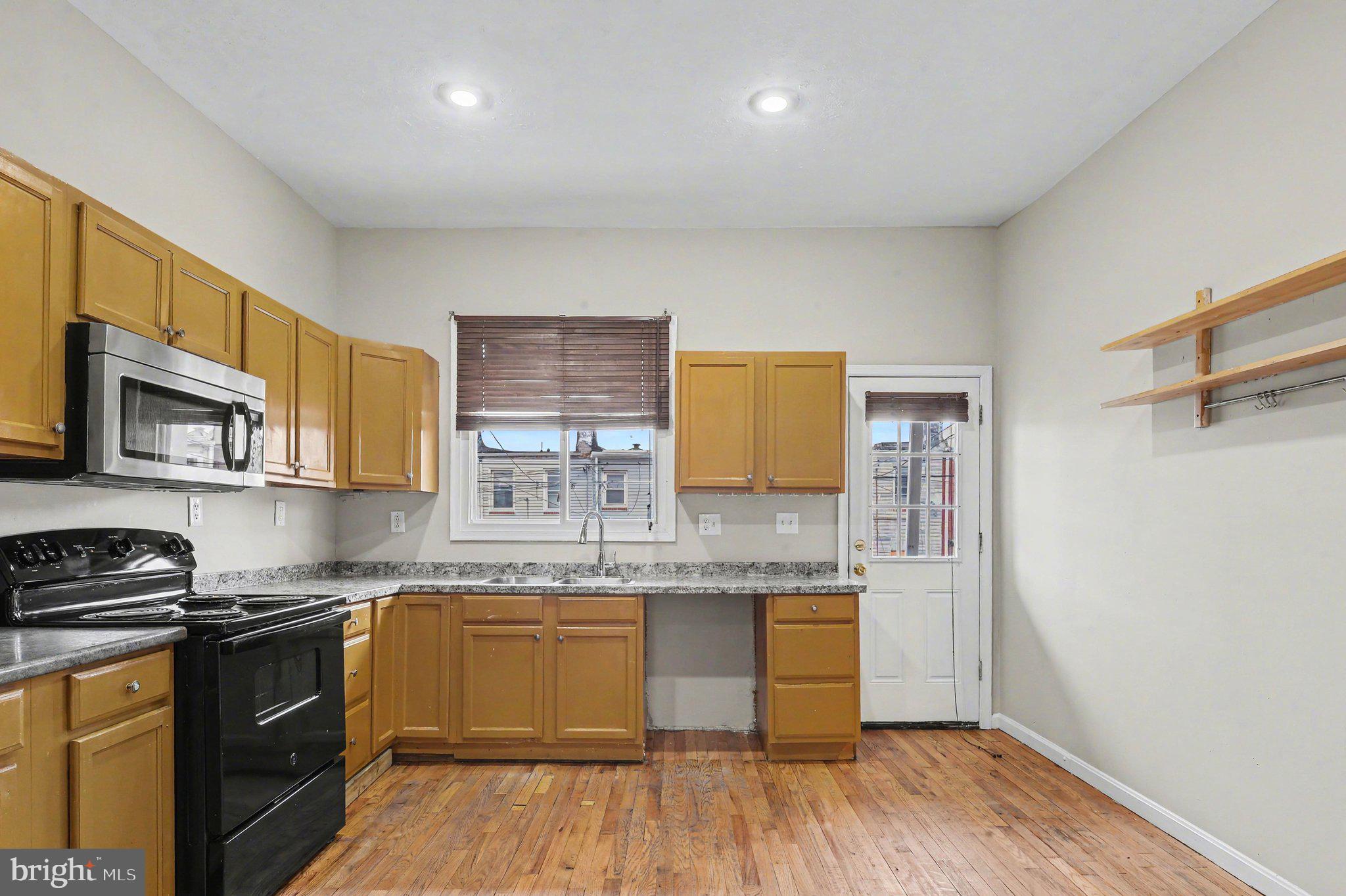 3418 East Baltimore Street Baltimore, MD 21224 - Photo 9 of 40 a kitchen with stainless steel appliances granite countertop a sink cabinets and wooden floor