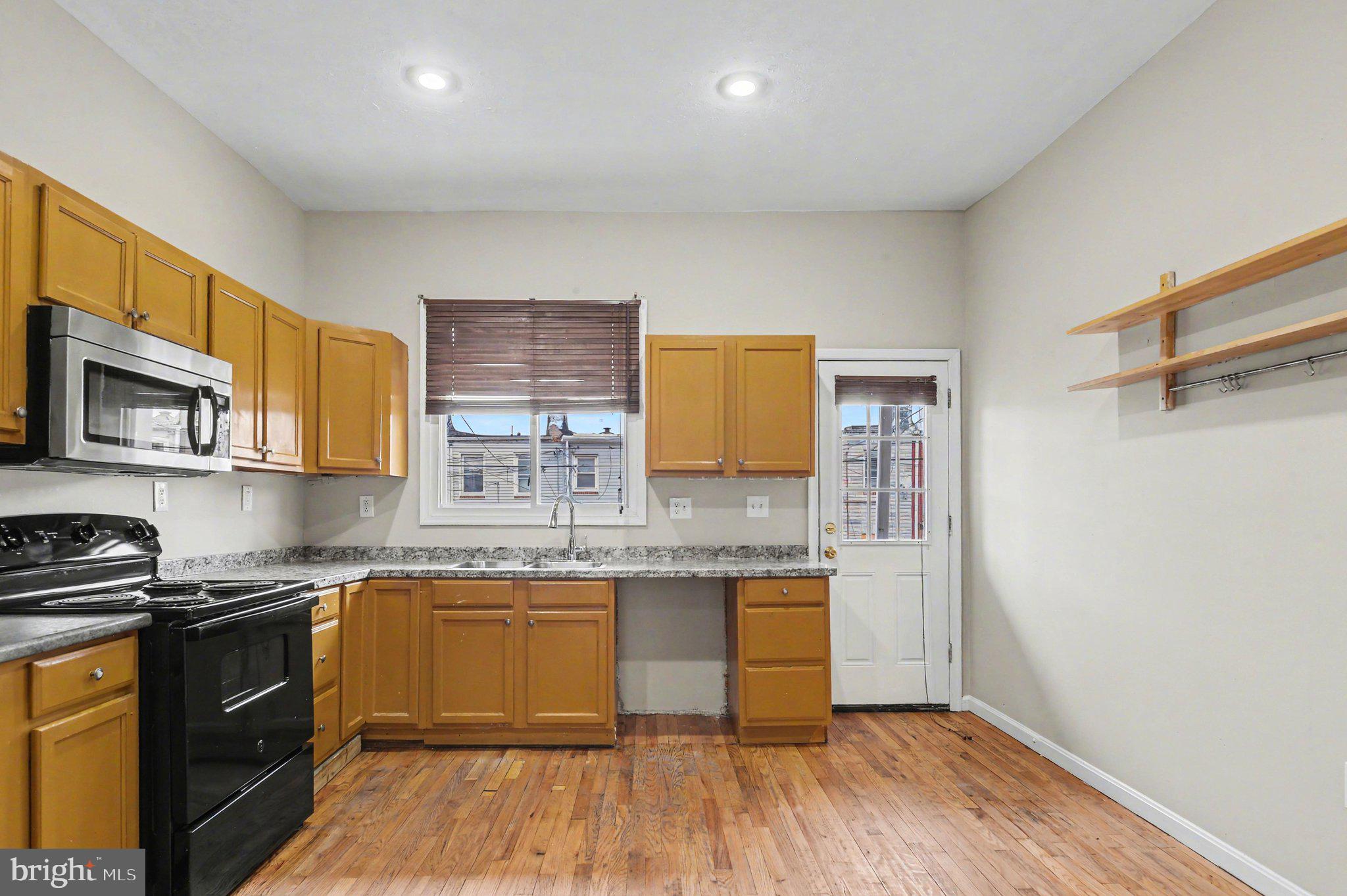 3418 East Baltimore Street Baltimore, MD 21224 - Photo 10 of 40 a kitchen with stainless steel appliances granite countertop a sink a stove a refrigerator cabinets and wooden floor
