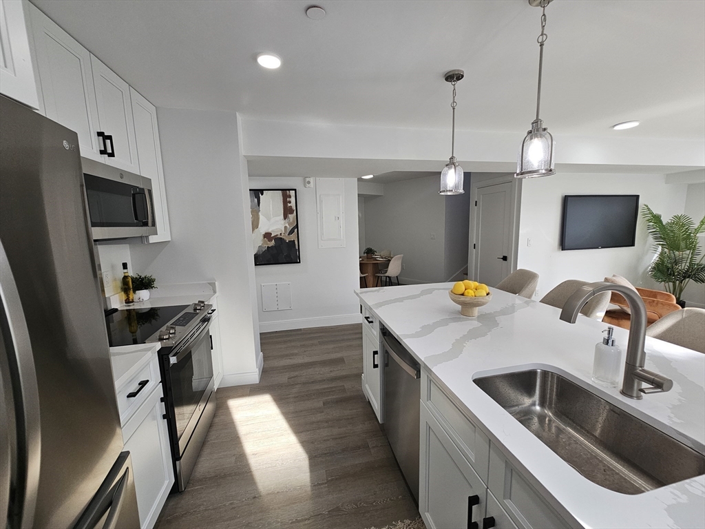 64 Alpine Street, Unit 104 Boston, MA 02119 - Photo 2 of 15 a kitchen that has a sink a microwave a stove and a refrigerator