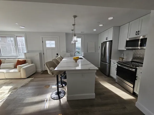 a living room with stainless steel appliances furniture a dining table and chairs in it