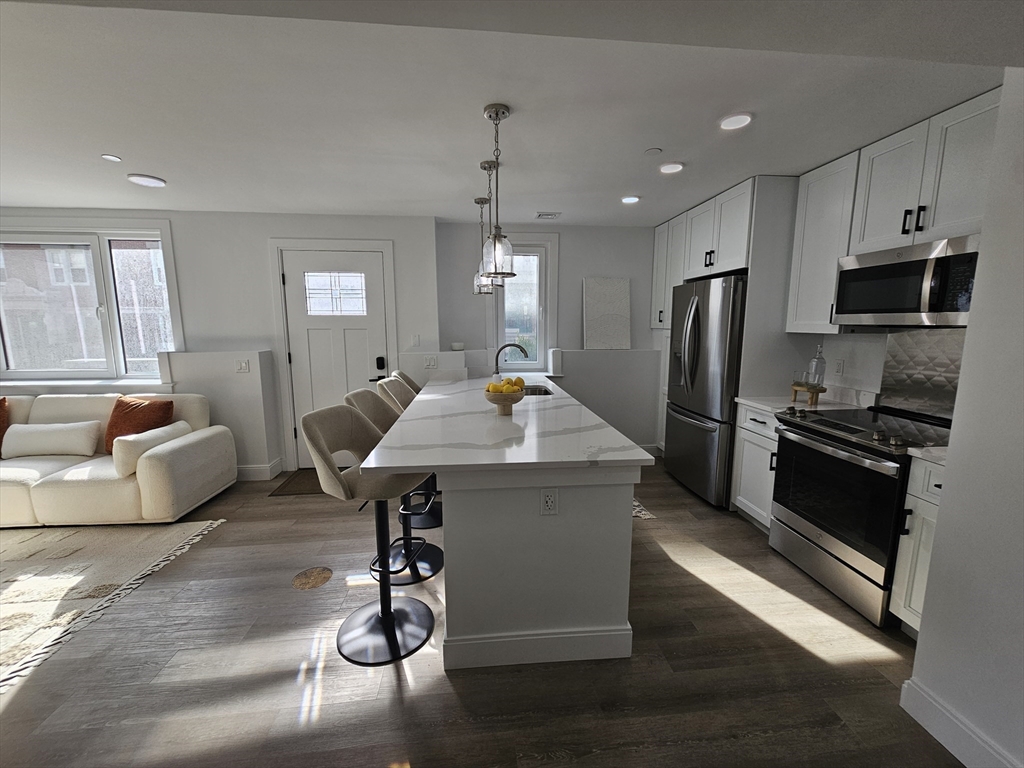 64 Alpine Street, Unit 104 Boston, MA 02119 - Photo 3 of 15 a living room with stainless steel appliances furniture a dining table and chairs in it