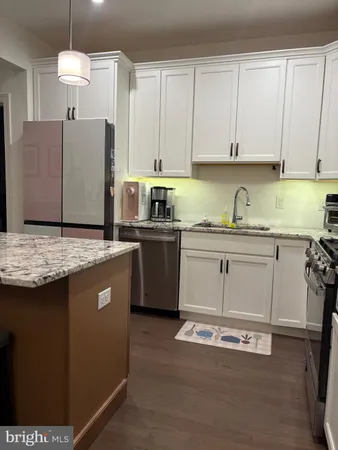 a kitchen with kitchen island granite countertop a sink a stove and cabinets