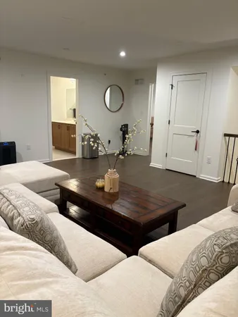 a living room with two couches chair and a dining table with wooden floor