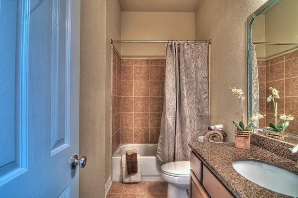 a bathroom with a granite countertop sink a toilet and shower
