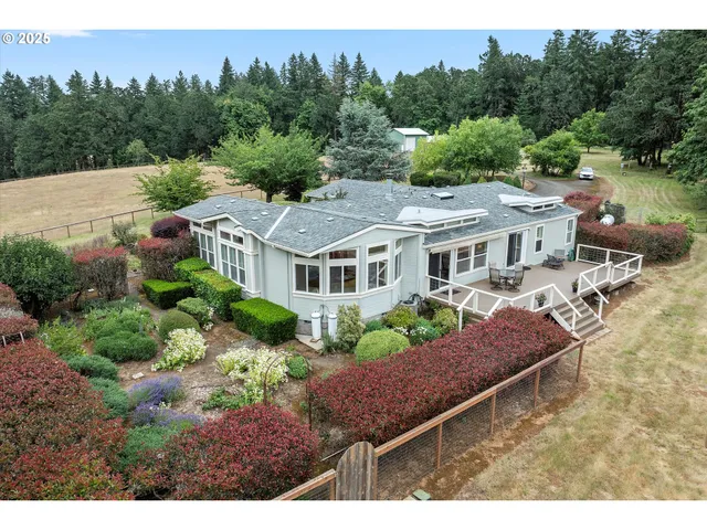 a view of a house with pool chairs and wooden fence