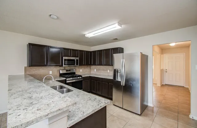 a kitchen with stainless steel appliances granite countertop a sink refrigerator and microwave