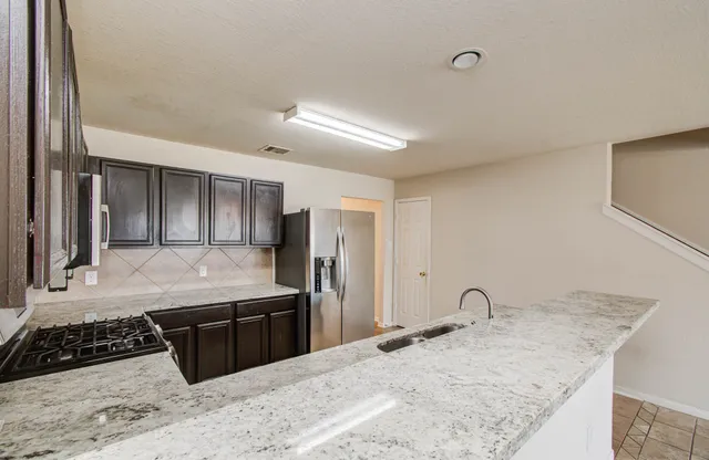 a kitchen with stainless steel appliances granite countertop a sink stove and refrigerator