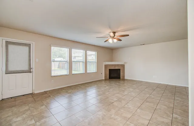 an empty room with windows and ceiling fan