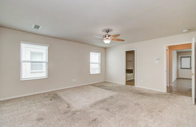 a view of an empty room with a chandelier fan