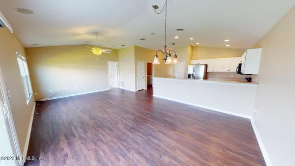 a view of a big room with wooden floor and a kitchen