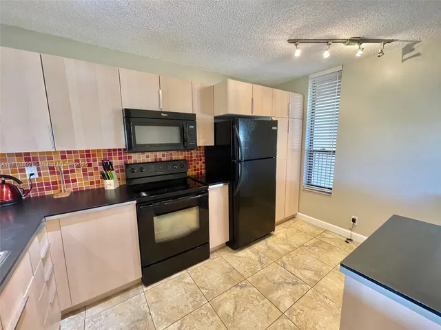 a kitchen with granite countertop a refrigerator and a stove top oven