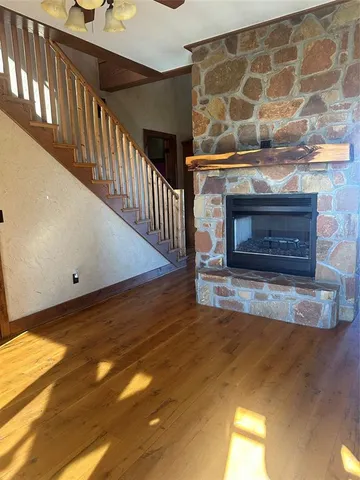 a view of an empty room with wooden floor and a fireplace