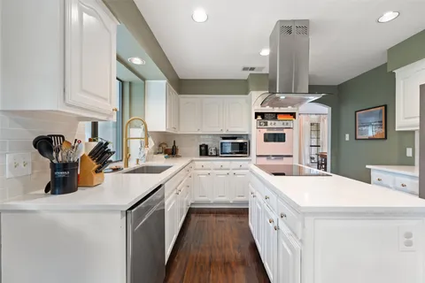 a kitchen with stainless steel appliances a stove a sink a chimney and a refrigerator