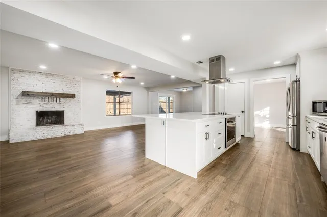 a large white kitchen with a lot of counter space and a wooden floor