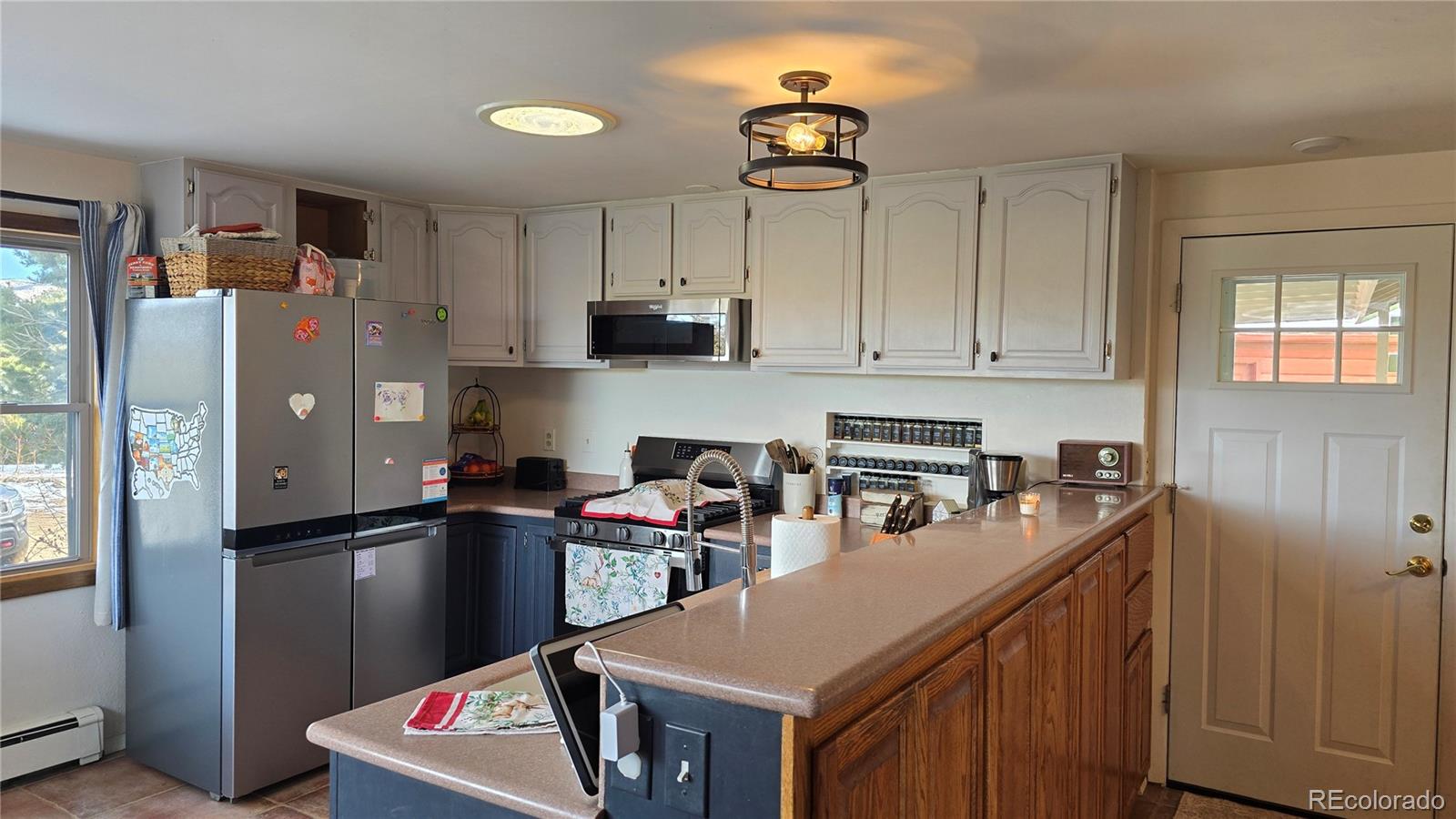 411 Gruenberg Road Fort Garland, CO 81133 - Photo 12 of 41 a kitchen with stainless steel appliances granite countertop a refrigerator a sink dishwasher a stove a dining table and chairs with wooden floor